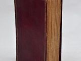 an old book sitting on top of a white table next to a white wall
