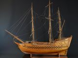 une maquette de bateau en bois posée sur un socle, sur fond noir