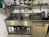 a stainless steel sink in a kitchen with pots and pans hanging on the wall