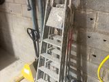 une échelle appuyée contre un mur, à côté d'un tas d'outils