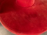 the red chair is next to a red vase on the table
