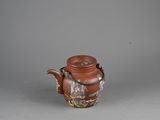 an image of a brown teapot with a handle on a gray surface