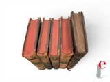 several old books are stacked on top of each other on a white surface