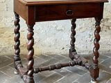 a small table with a drawer on it on a brick floor
