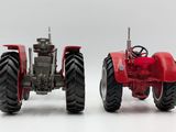two red tractors sitting side by side on a white surface