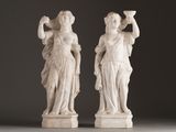 pair of white marble statues of a woman and a man holding cups