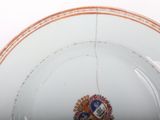 a white plate with an orange border and a picture of a coat of arms on it