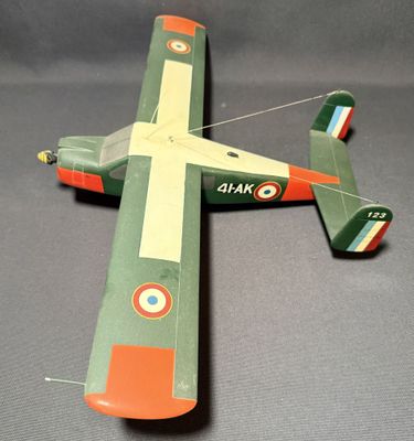 une maquette d'avion vert et orange posée sur une surface grise