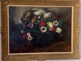 un tableau accroché au mur d'une pièce où se trouve un vase de fleurs