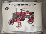 une photo d'une brochure présentant un tracteur, posée sur un plancher en bois