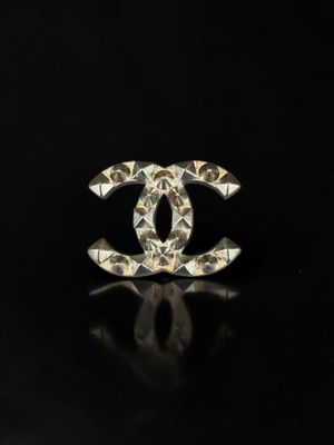 a close up of a chanel broocher on a black surface