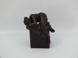 statue of a man sitting on a box with his head resting on a woman ' s back