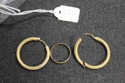 three pairs of gold hoop earrings on a black surface