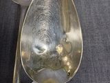two silver spoons with tags on them sitting on a table