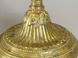 a gold candle holder with a candle on top of it