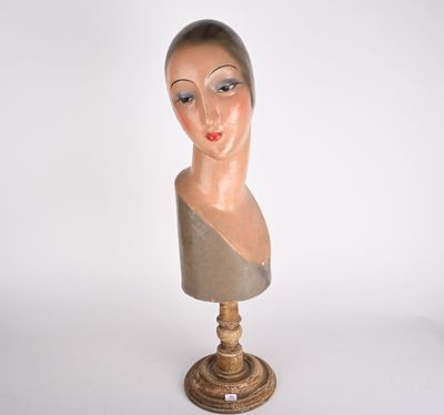 une tête de mannequin posée sur un socle en bois, sur fond blanc