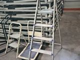 a close up of a metal ladder in a warehouse with a stack of chairs
