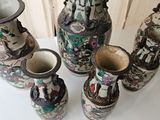 five vases sitting on a white table with a curtain in the background