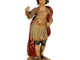 une vieille statue représentant un homme vêtu d'une robe et coiffé d'un chapeau