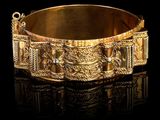 gros plan d'un bracelet en or sur une surface noire