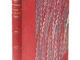 un vieux livre à la couverture rouge posé sur une table blanche