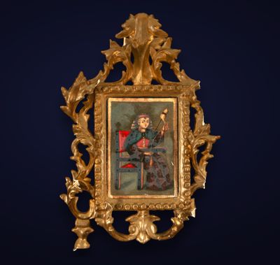 an ornate gold frame with a painting of a man sitting on a red chair