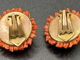 pair of gold and coral colored earrings on a black surface