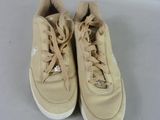 pair of beige sneakers with white soles on a white surface