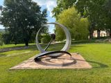 a metal sculpture in the middle of a grassy area