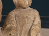 a statue of a man sitting on a rock next to a vase