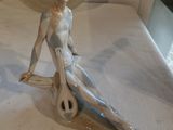 une figurine de femme assise sur une planche de surf