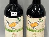 two bottles of red wine sitting next to each other on a table