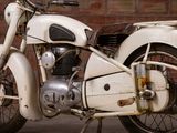 a white motorcycle parked in front of a brick wall
