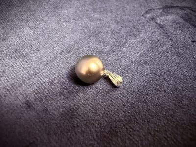 a golden ball with a tassel on it on a gray surface