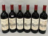 six bouteilles de vin sont alignées sur une table