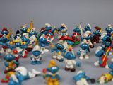 toy figurines of smurfs are lined up on a gray surface
