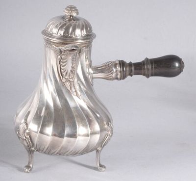 une cafetière en argent posée sur un support et munie d'une poignée en bois