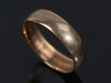 a close up of a gold wedding ring on a black surface