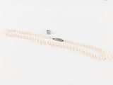 un collier de perles blanches avec un fermoir en diamant, sur fond blanc