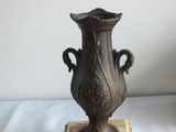 a bronze vase sitting on top of a marble block