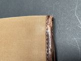 the back of a chair with a brown leather seat and arm rest