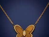 a gold butterfly necklace with a diamond on a chain
