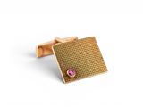 a close up of a pair of gold cufflinks with a pink stone