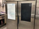 un grand réfrigérateur en acier inoxydable dans une cuisine dont la porte est ornée d'un tableau noir