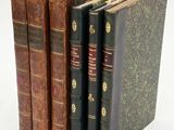 several old books are stacked on top of each other on a white surface