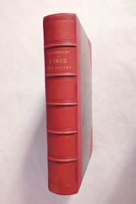un vieux livre rouge posé sur une surface blanche