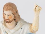 a figurine of jesus holding his hands up in the air