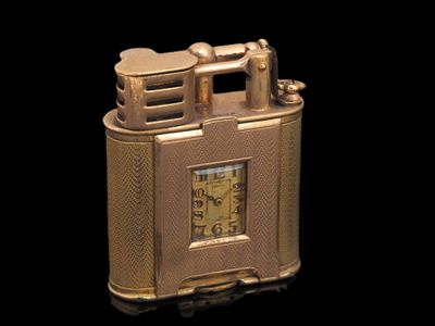 un briquet doré orné d'une horloge, sur fond noir