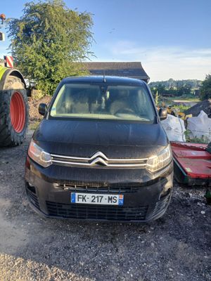 une petite voiture garée à côté d'un tracteur sur le bord de la route