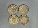 quatre types différents de pièces d'or sur une surface grise